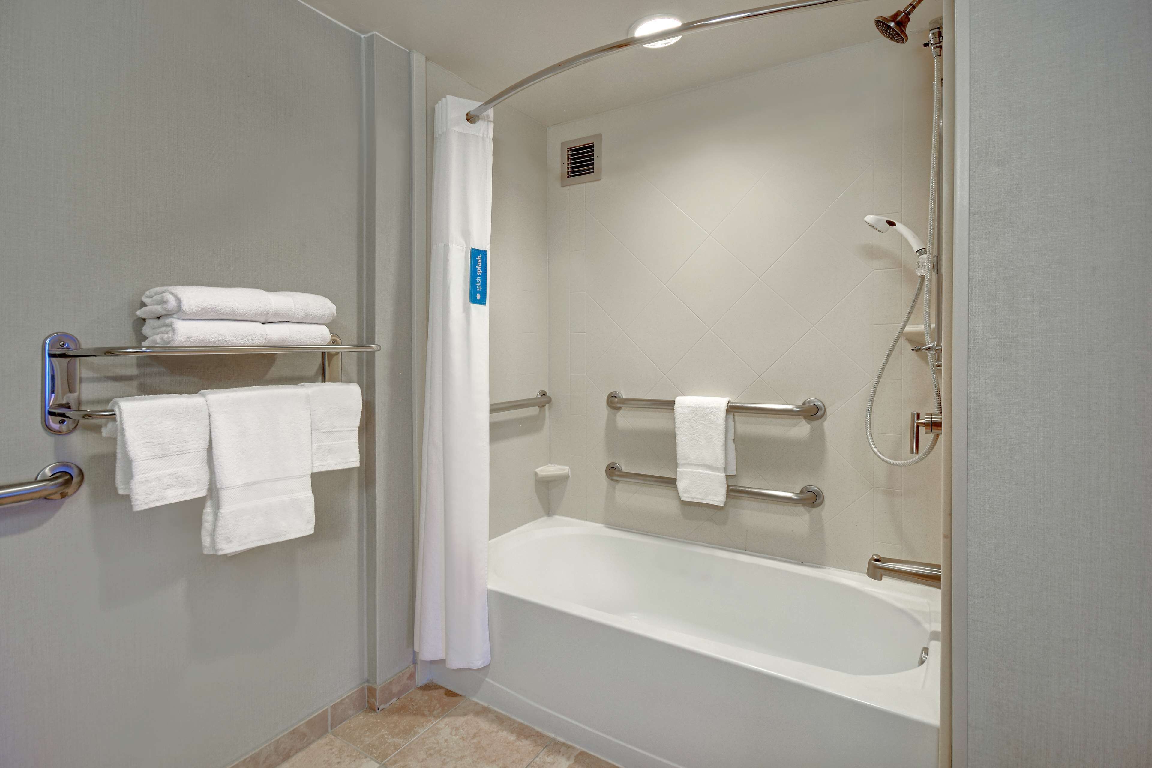Un bagno moderno con una vasca, una doccia e mancorrenti.