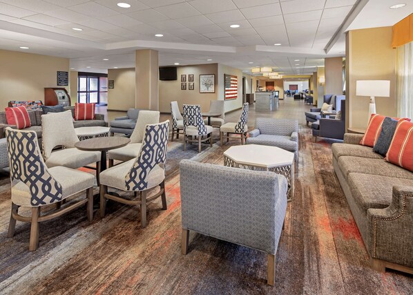 A hotel lobby with seating areas, a reception desk, and an American flag on the wall. - Hampton Inn & Suites Alexandria Old Town Area South (Alexandria)