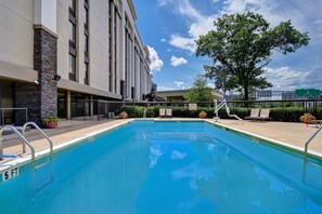A rectangular swimming pool with a metal ladder on one side, surrounded by a fence. There are lounge chairs and potted plants on the adjacent patio area. - Hampton Inn & Suites Alexandria Old Town Area South (Alexandria)
