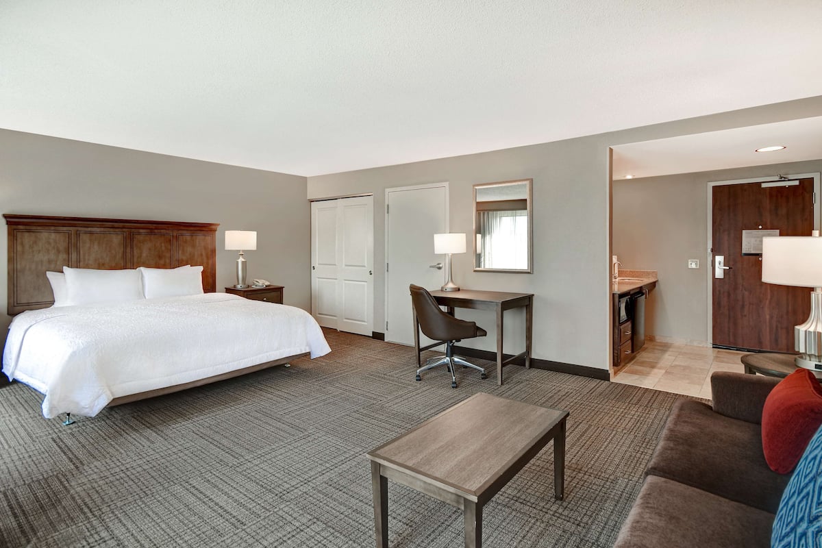A hotel room with a bed, desk, chair, and a small table.