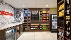 A store with a 'SWEET SHOP' sign, shelves stocked with snacks, beverages, and a refrigerated display. - Hampton Inn & Suites Alexandria Old Town Area South (Alexandria)