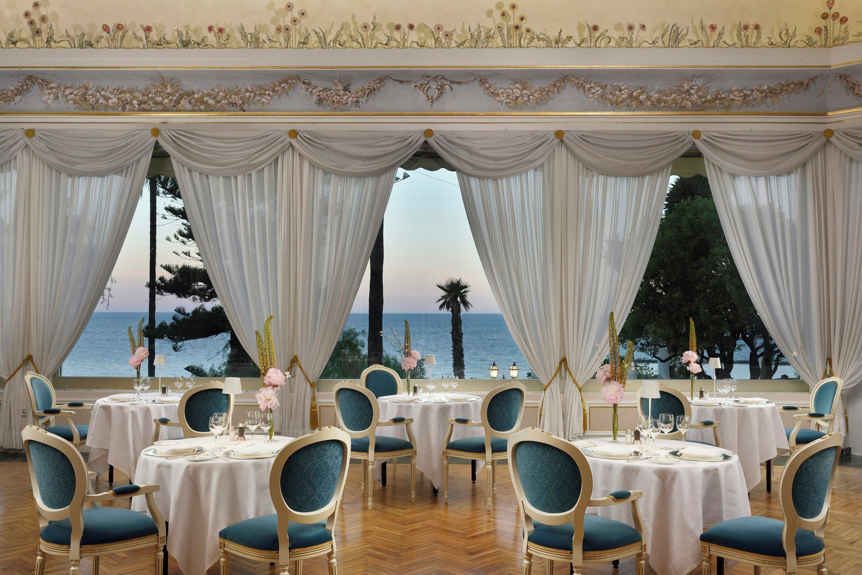 A dining area with tables set for service, overlooking a body of water.