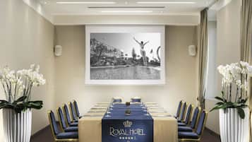 A conference room with a long table, blue chairs, and a framed photograph on the wall.