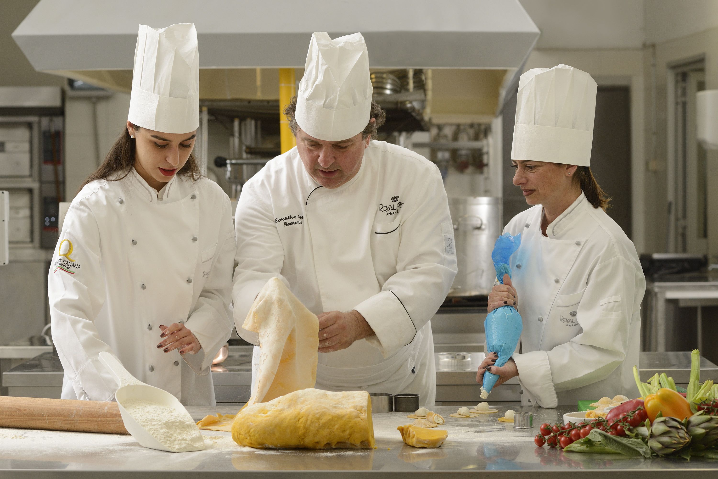 Three chefs in a professional kitchen preparing food.