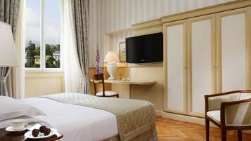 Una habitación de hotel con cama, televisión, escritorio con lámpara y una silla.