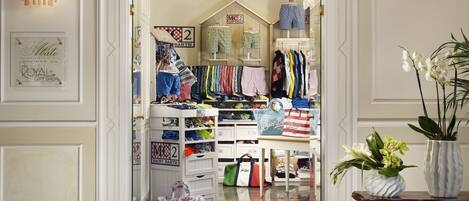 Una tienda de regalos boutique bien organizada, con ropa y accesorios ordenados, incluyendo una variedad de bolsos y una exhibición de pantalones cortos estampados.