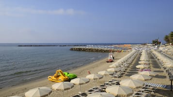 Vlak bij het strand, ligstoelen aan het strand, parasols, strandlakens