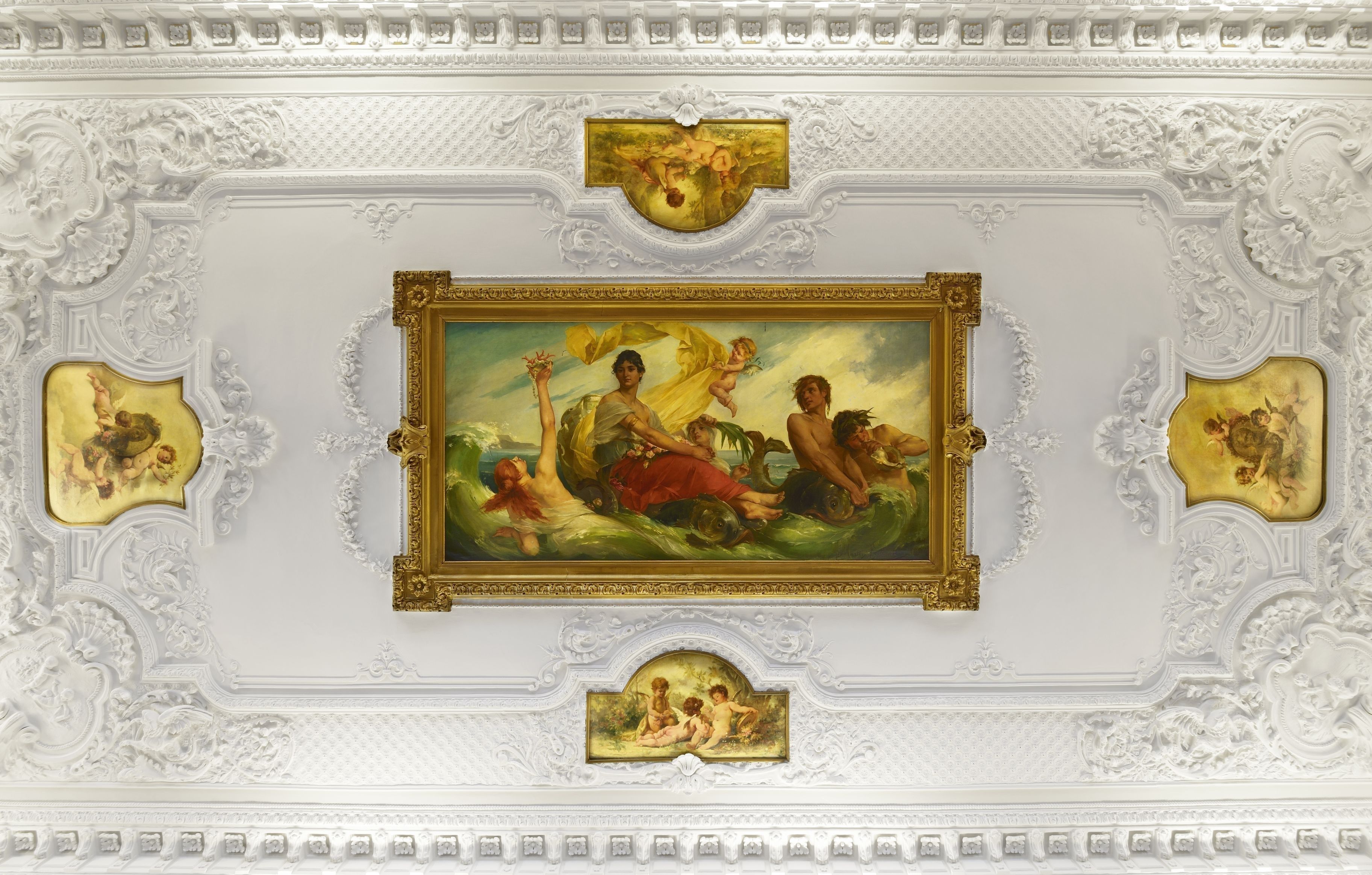 A ceiling with ornate white plasterwork and gold-framed paintings depicting classical scenes.