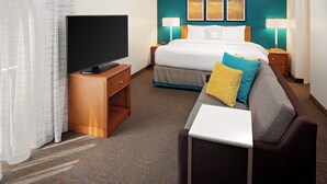 Ein Hotelzimmer mit Bett, Fernseher, Schreibtisch und einer Couch.