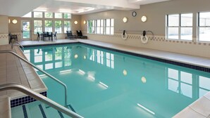 Ein Schwimmbad mit klarem Wasser, einem Rettungsring und einer Uhr an der Wand.