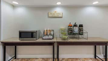 A kitchenette with a microwave, coffee maker, and a sign that says "FRESH COFFEE SERVED HERE".