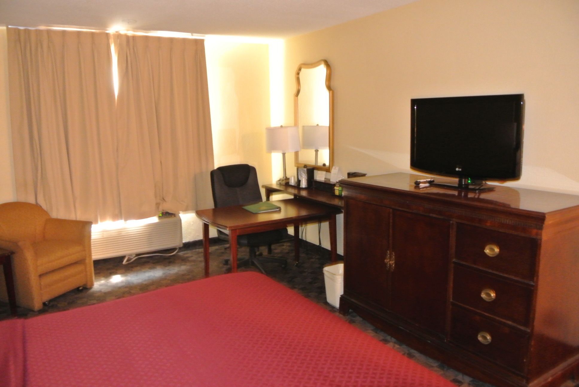 A hotel room with a bed, a desk, a chair, a television, and a wardrobe.