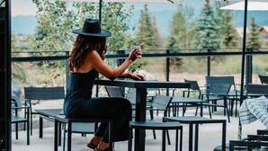 Una mujer sentada a una mesa con vista a árboles y montañas.
