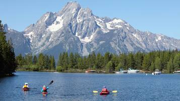 Kayakers on a calm lake with a mountain range in the background.