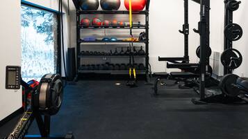 Une salle de sport équipée de matériel de musculation, de ballons d’exercice et d’un rameur.