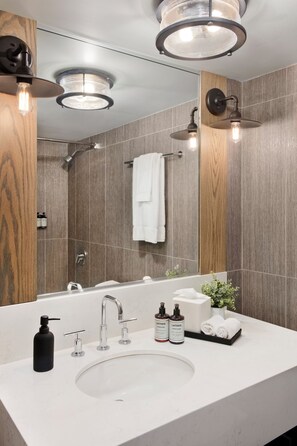 A modern bathroom with a large mirror, a white sink, and a shower area.