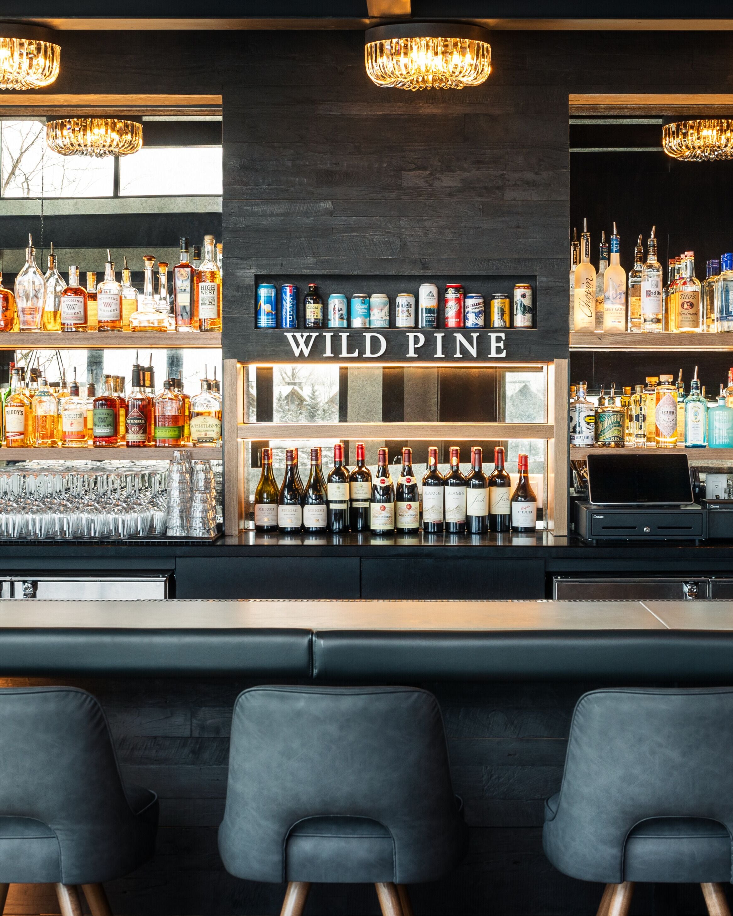 A bar area with a sign reading "WILD PINE" above shelves stocked with various bottles and glasses.