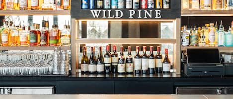 A bar area with a sign reading "WILD PINE" above shelves stocked with various bottles and glasses.