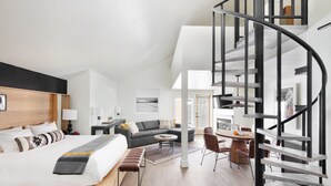 Una habitación de hotel moderna con una cama grande, un sofá, una zona de comedor y una escalera en espiral.