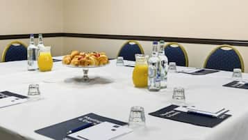 A conference room with a long table set for a meeting, including a fruit platter, juice, and water bottles.