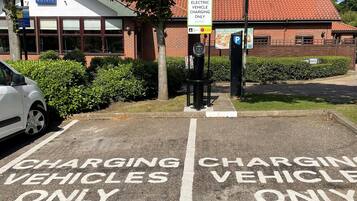 A parking area with 'Electric Vehicle Charging Only' signs and a 'Hand Stretch' sign.