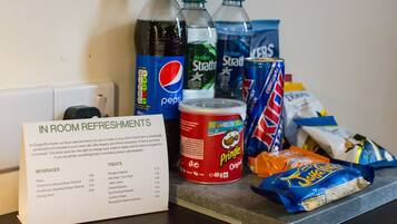 Een tafel met een menukaart waarop dranken en lekkernijen staan, waaronder Pepsi, Strathmore Mineraalwater en Pringles.