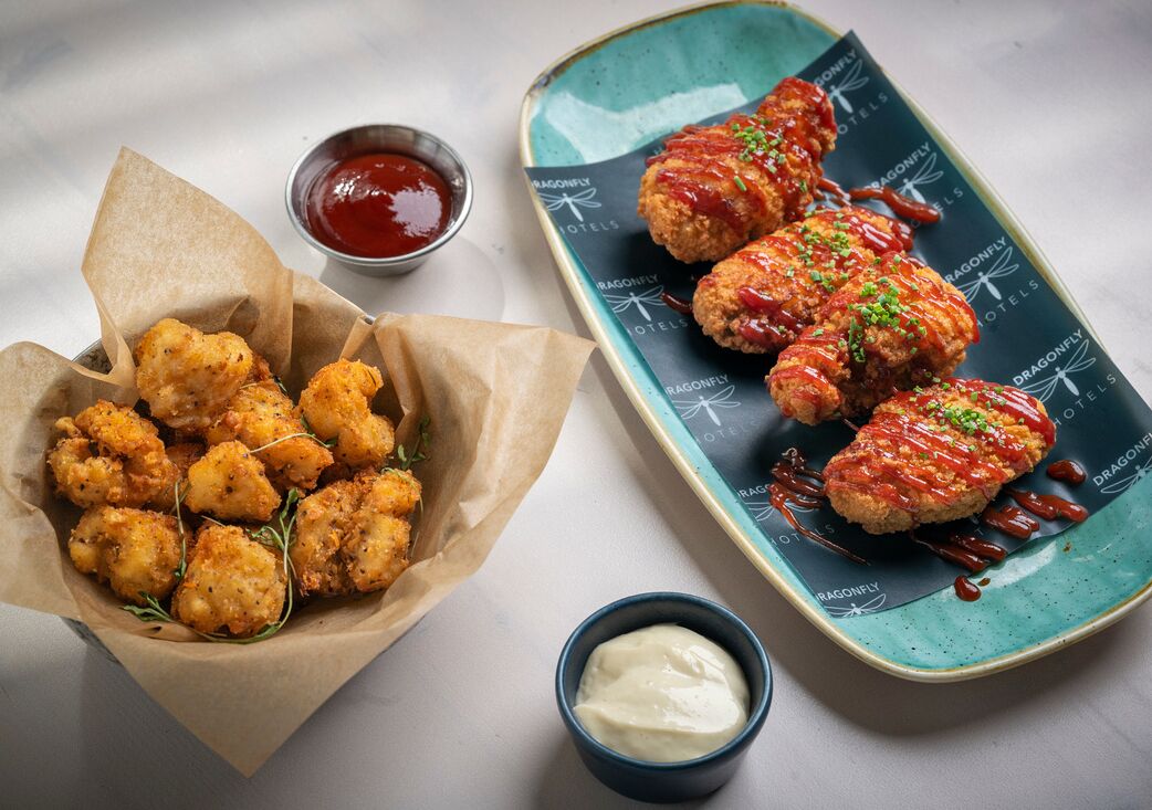 A tray of breaded and fried chicken tenders with a side of ketchup and a small bowl of sauce.