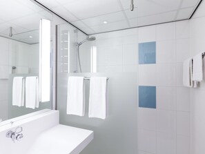 Une salle de bain moderne avec une douche à parois de verre, un lavabo blanc et un miroir.