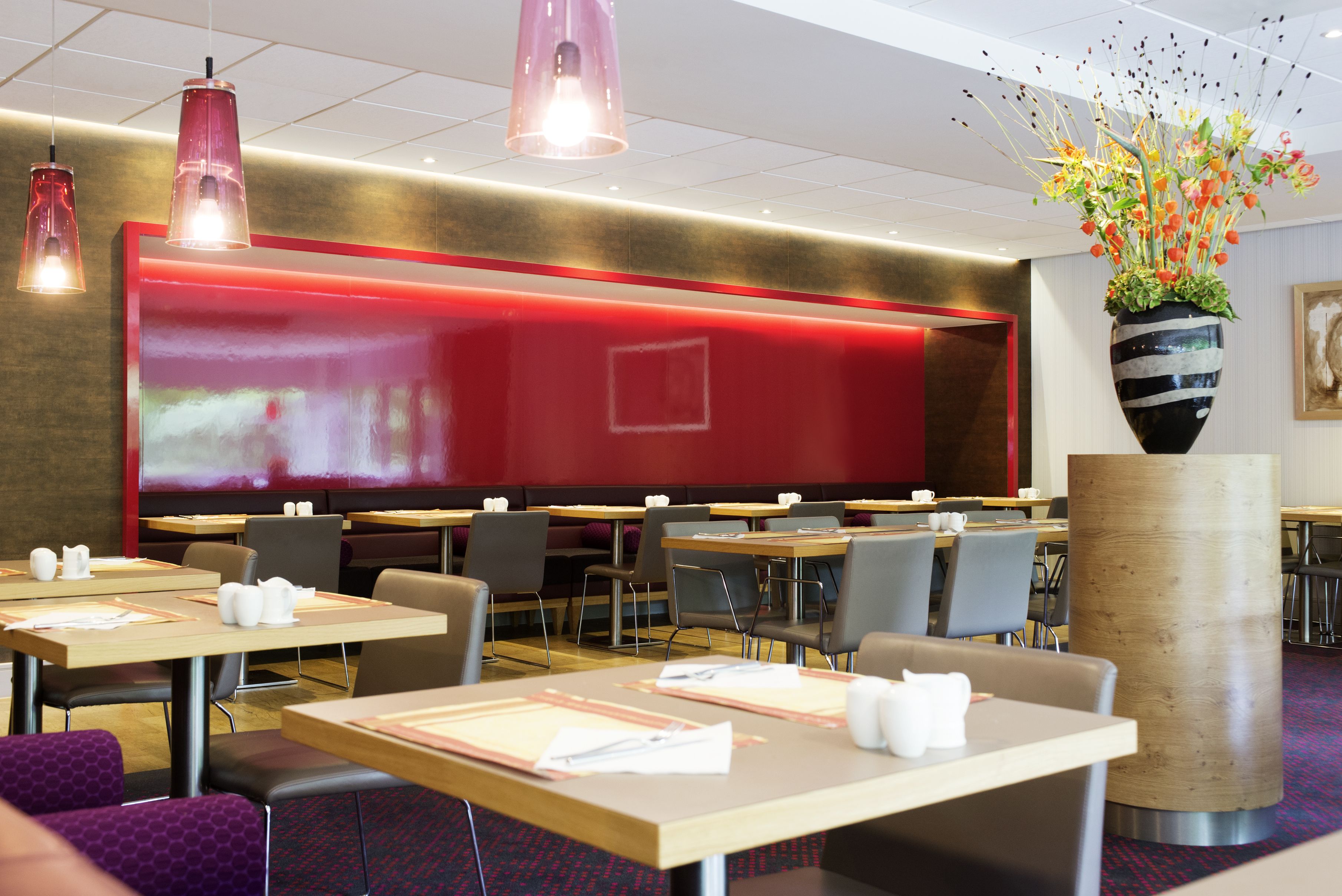 A modern dining area with tables, chairs, and a large screen.