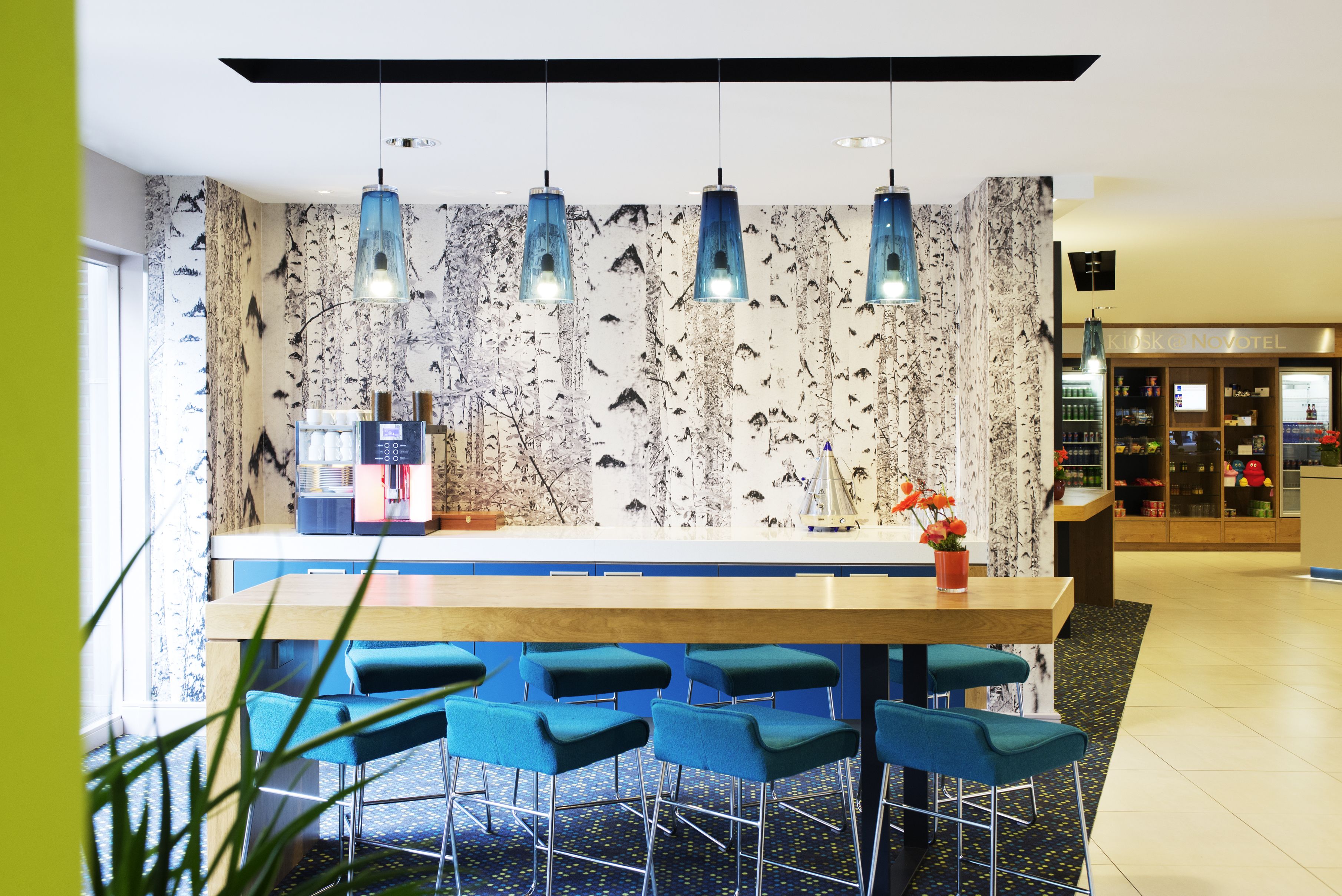 Eine moderne Bar mit Marmorwand, blauen Barhocker und Pendelleuchten.