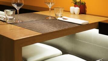 A dining table with a placemat, two wine glasses, a water glass, and a napkin.