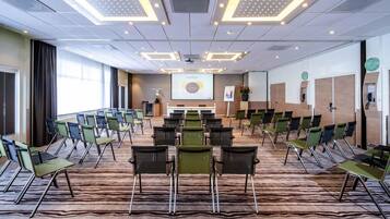 A conference room with a zebra-patterned carpet, multiple rows of chairs, a podium, and a presentation screen.