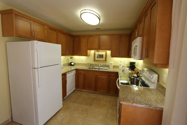A kitchen with wooden cabinets, a white refrigerator, a stove, and a microwave.