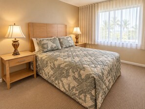 Habitación de hotel con cama, dos mesitas de noche, lámparas, una ventana con cortinas y suelo alfombrado.