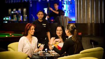 Zona de bar amb billar, tamborets i un barman.