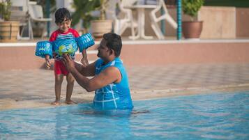 Guests can enjoy a refreshing swim in the pool surrounded by lush greenery and comfortable seating.