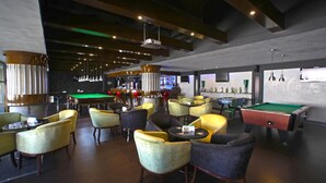 A spacious lounge area with multiple seating options, a pool table, and a bar area with a television. - Hotel Muscat Holiday (Muscat)