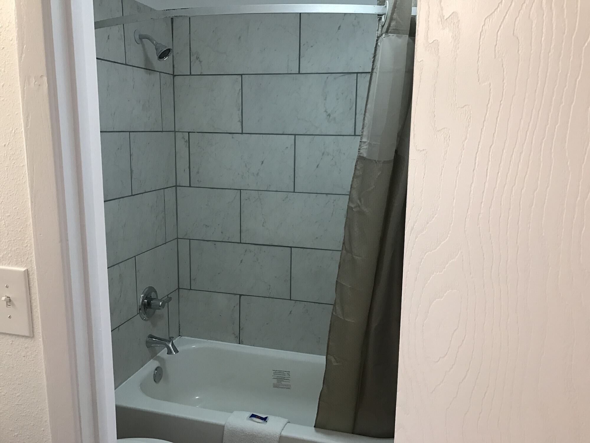A bathroom with a bathtub, shower, and tiled walls.
