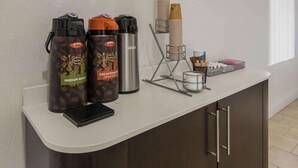 Una estación de café con dos dispensadores, una balanza y una pila de vasos desechables.