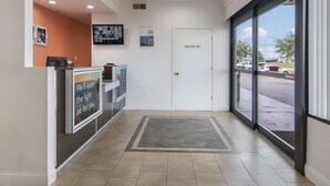 Un área de recepción con un mostrador, una puerta que indica 'Sólo para empleados' y vista al estacionamiento.