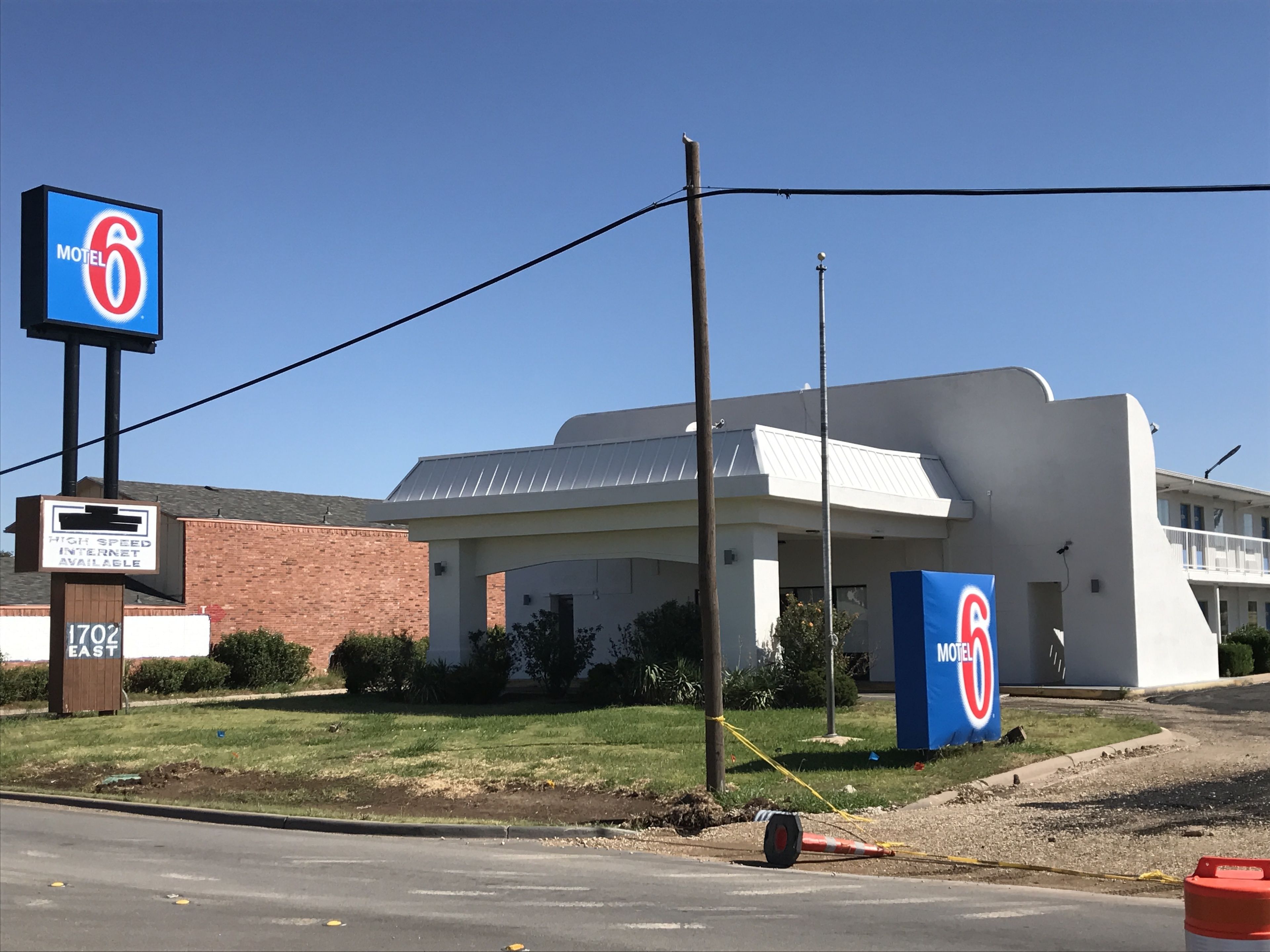 Un letrero de Motel 6, un edificio con diseño moderno, y un anuncio que indica disponibilidad de internet de alta velocidad.