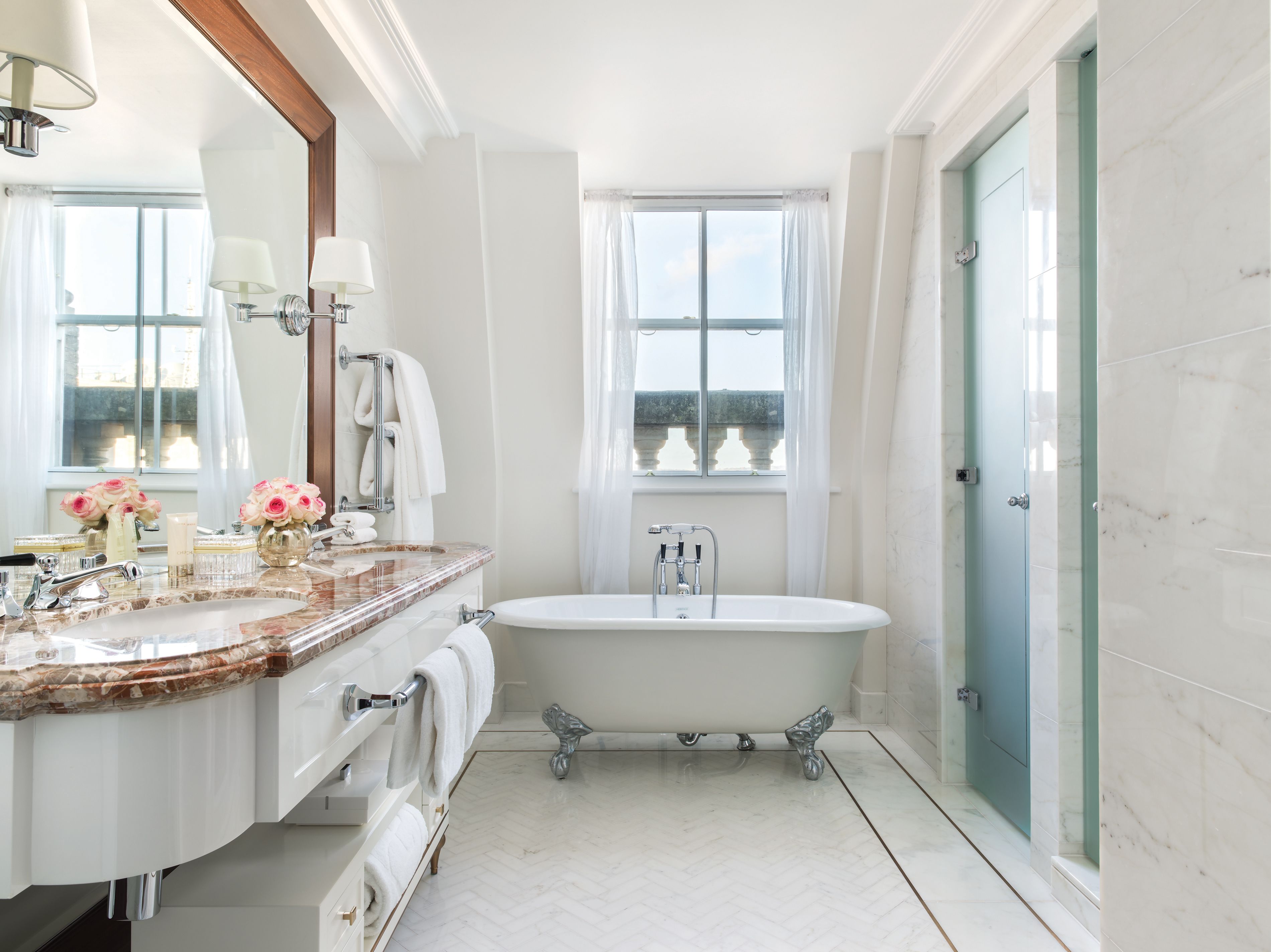 A bathroom with a marble sink, a freestanding bathtub, and a large window with a view.