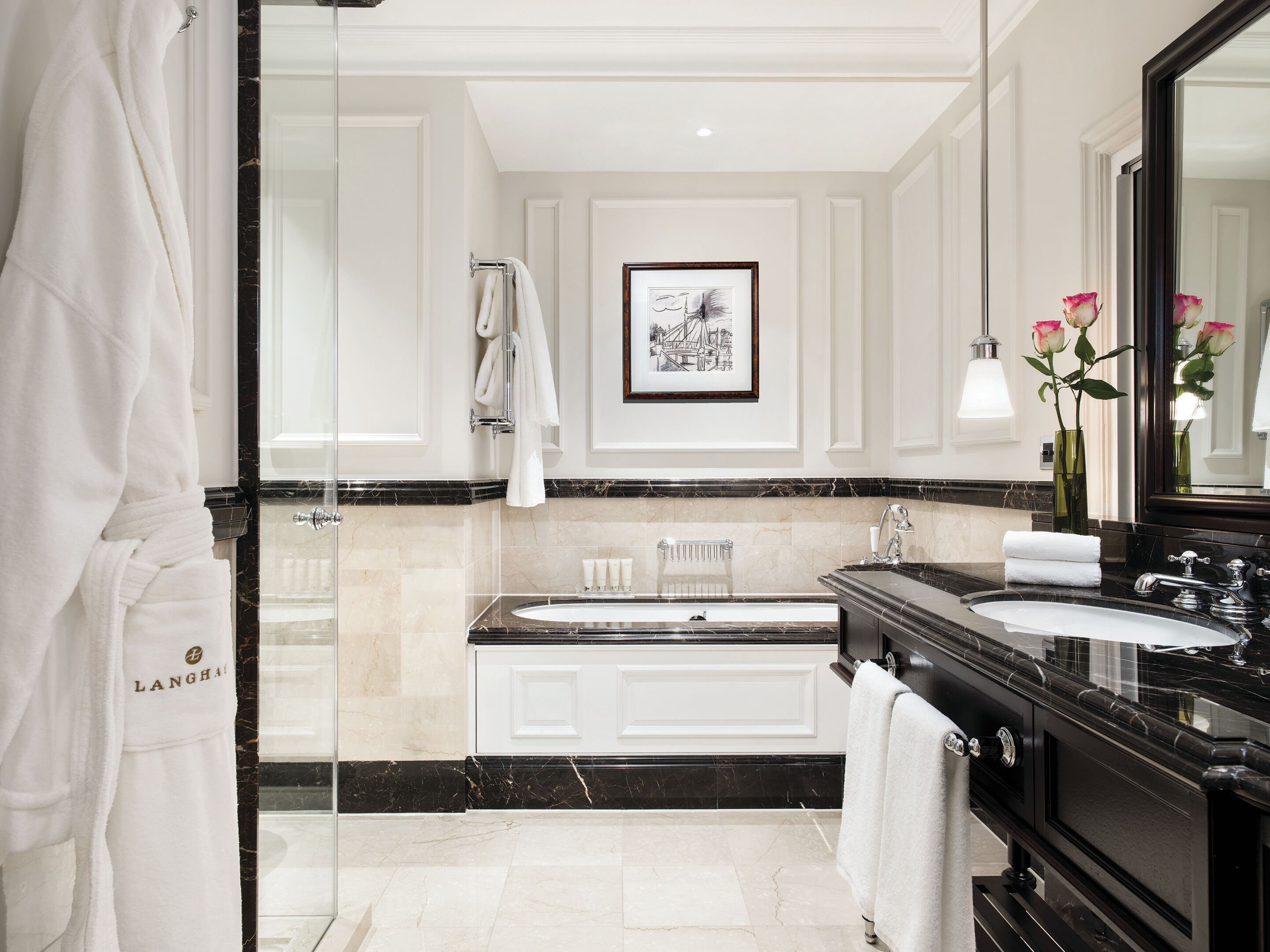 A luxurious bathroom with a large mirror, a double sink vanity, and a framed picture on the wall.