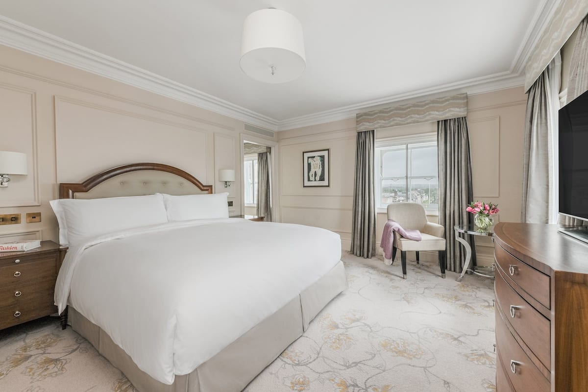 A hotel room with a large bed, a chair, a dresser, and a television.