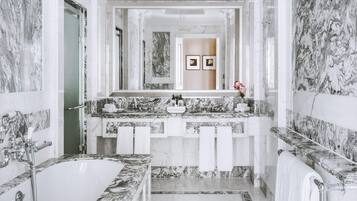 Ein luxuriöses Badezimmer mit einer großen Marmorbadewanne, einem Doppelwaschtisch und einem großen Spiegel.