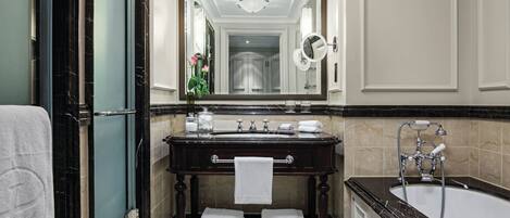 Une salle de bain luxueuse avec un meuble-lavabo en marbre, un grand miroir, une baignoire et un porte-serviettes.