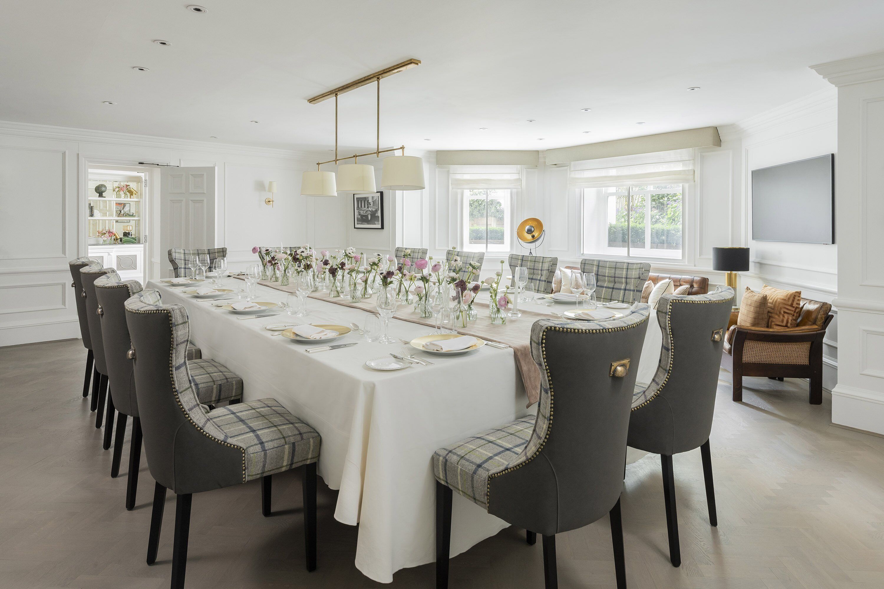A dining room with a long table set for a meal, surrounded by chairs.