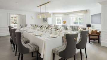A dining room with a long table set for a meal, surrounded by chairs.