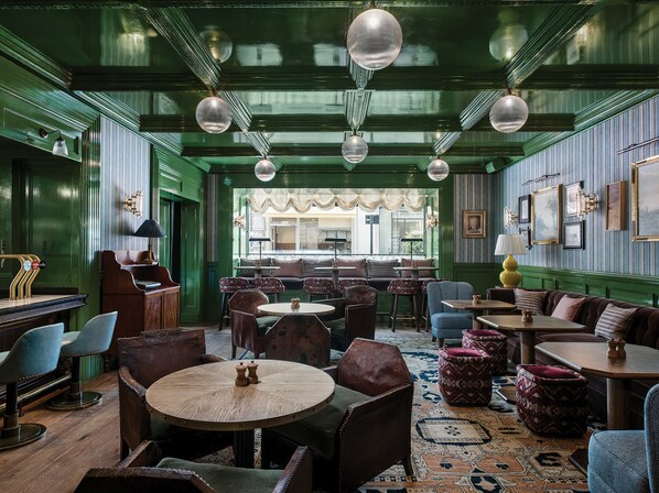 A traditional interior with green walls, multiple seating areas, and hanging spherical light fixtures. - The Langham, London (London)