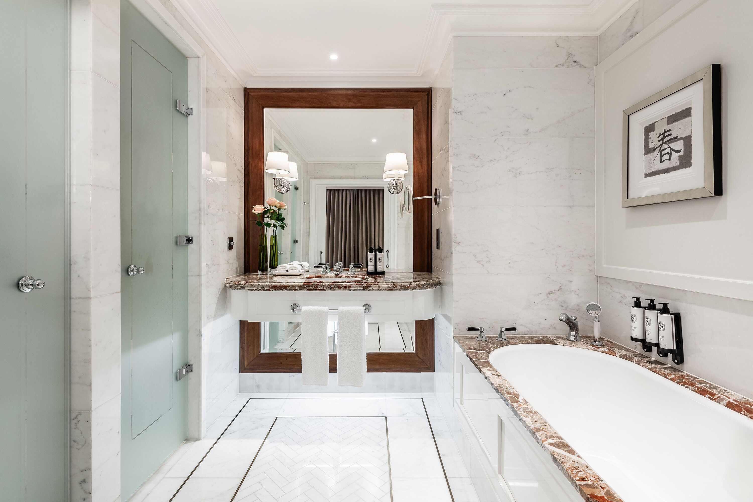 Un bagno moderno con un elegante mobile in marmo, un ampio specchio, una vasca da bagno e un quadro appeso al muro.